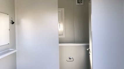 Innenansicht Herren-WC im WC-Container mit Waschbecken, Spiegel, WC-Kabine.