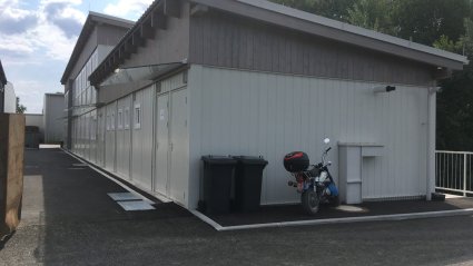 Zweist&ouml;ckige und einst&ouml;ckige Containerb&uuml;ro-Anlage aus wei&szlig;en Modulen mit Glas&uuml;berdachungen &uuml;ber den Eingangst&uuml;ren und Pultd&auml;cher
