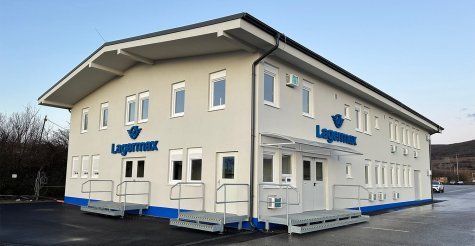 Zweistöckiges Containerbüro mit Feinputzfassade, blauer Sockelputz, Zugangspodeste zu den Eingängen und überdachter Portierbereich