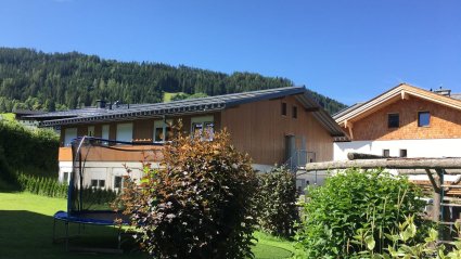 Zweigeschoßiger Wohncontainer Modulbau mit weißen Modulen im Erdgeschoß, Holzfassade im Obergeschoß, Außentreppe und Satteldach