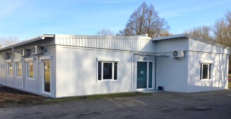 Außenaufnahme einer einstöckigen Kindergarten Containeranlage aus weißen Modulen mit Satteldach und Attika