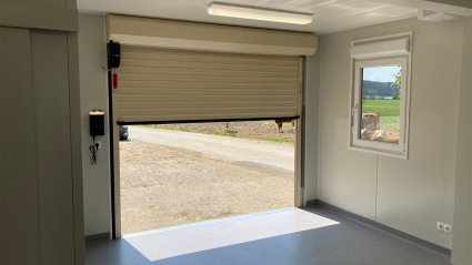 Innenansicht eines halb ge&ouml;ffneten Rolltors in einer Containeranlage