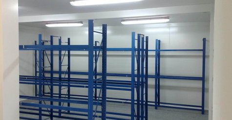 Innenansicht eines zweist&ouml;ckigen Reifenlagers aus Raummodulen mit blauen Reifenregalen und Beleuchtung.