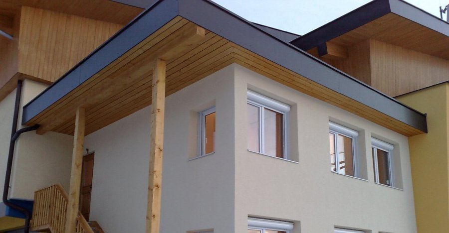 Zweigeschossige Wohncontaineranlage, Fassade mit Feinputz, Holz-Stahl Außentreppe, Flachdach mit Holzschalung