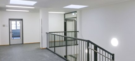 Heller Flurbereich eines modularen Gebäudes mit verschiedenen Wand- und Deckenleuchten