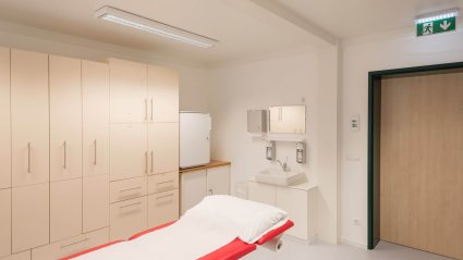 Behandlungsraum in einem Krankenhaus-Modulbau mit Behandlungsliege, Schranksystem und Waschbereich