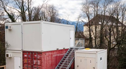 Zweigescho&szlig;ige Baucontainer-Anlage bestehend aus drei wei&szlig;en 20-Fu&szlig; B&uuml;rocontainern, einem roten 20-Fu&szlig; Seecontainer, einem 10-Fu&szlig; WC Container und Stahltreppe