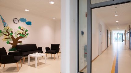 Gang mit angrenzendem Eltern-Wartebereich in einem Kindergarten-Modulbau mit hellem Boden, hellen Wänden und Sitzgelegenheit