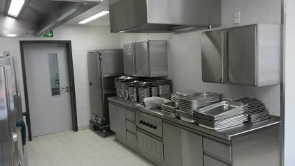 Geflieste Schulk&uuml;che mit Edelstahlschr&auml;nken und Dunstabzugshaube