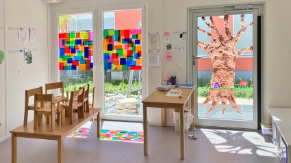 Gruppenraum in einem Kindergarten-Modulbau ausgestattet mit kindgerechten M&ouml;beln, hellem Vinylboden, wei&szlig;en W&auml;nden und Terrassent&uuml;ren