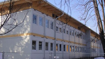 R&uuml;ckansicht einer zweist&ouml;ckige Krankenhaus-Containeranlage als Seniorenwohnheim aus wei&szlig;en Modulen, mit Pultdach und Attika