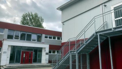 Seitenansicht zweigeschossiger Schulcontainer-Modulbau mit Stahl-Au&szlig;enstiege zur Notausgangst&uuml;r im Obergeschoss