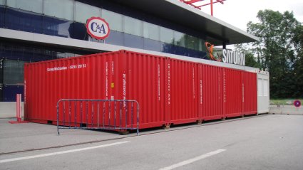 R&uuml;ckansicht von 5 roten 20-Fu&szlig; Lagercontainern und einem wei&szlig;en 20-Fu&szlig; B&uuml;rocontainer