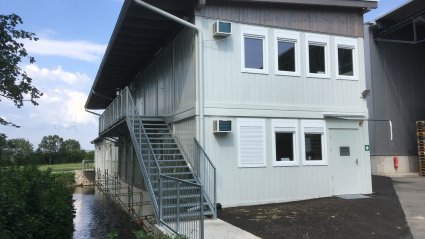 Zweist&ouml;ckige B&uuml;rocontaineranlage aus wei&szlig;en Modulen mit Au&szlig;entreppe, Zugangspodest und Pultdach